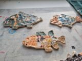 Beispielfoto, zu sehen sind 3 Fische, die von Kindern aus Keramik gemacht wurden und mit bunten Farben glasiert wurden.