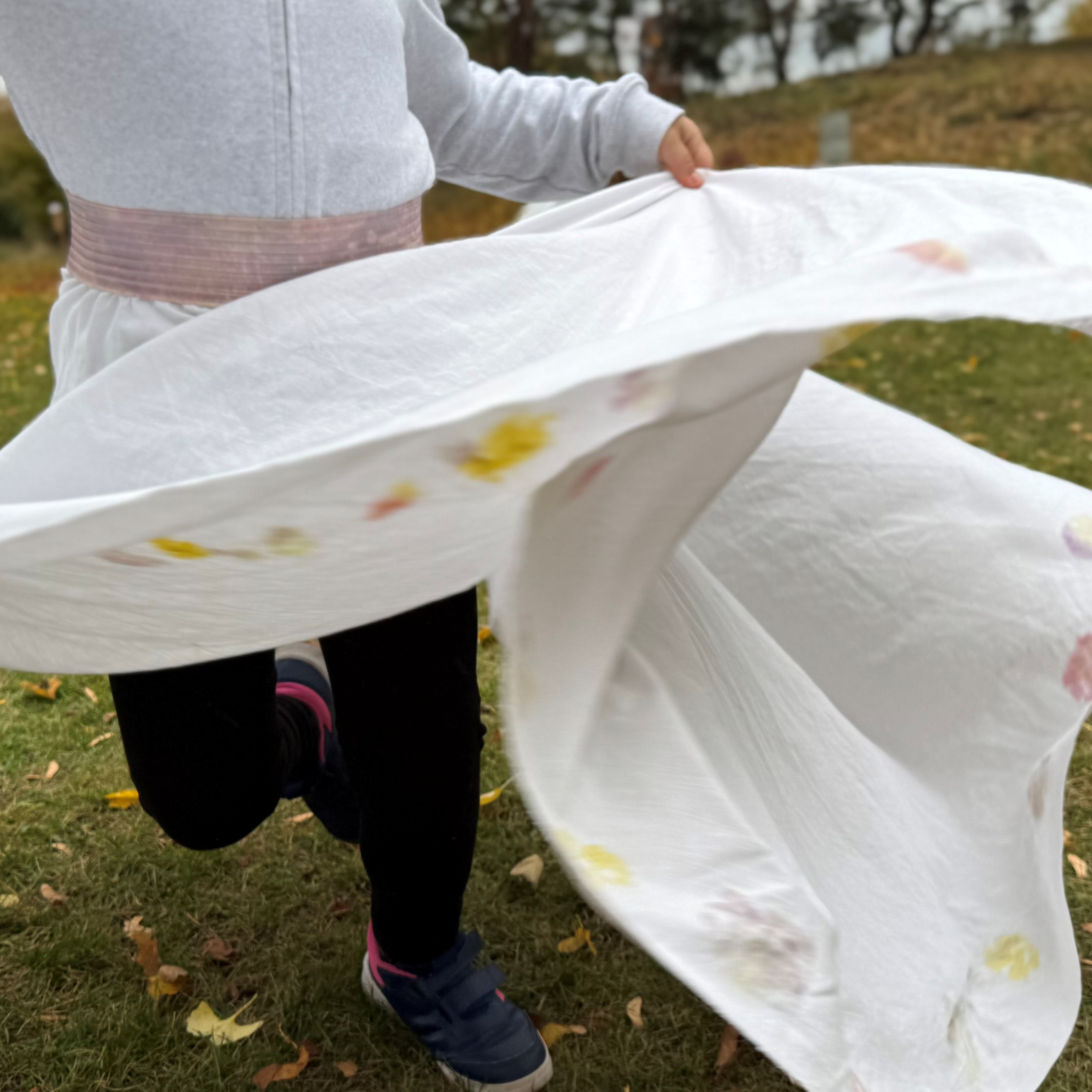 Ein Kind rennt in einem wehenden weißen Kleid über eine Wiese.